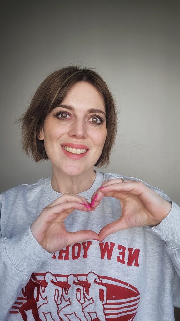 Laura Roth, Autorin humorvoller Liebesromane, lächelndes Porträt mit Herzgeste